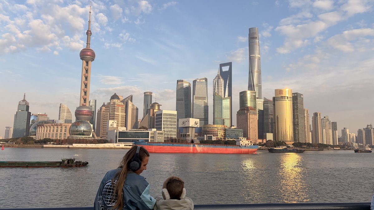 Bunny Hedaya worldschooling her son overlooking the Shanghai skyline at sunset, representing family travel content across 35+ countries